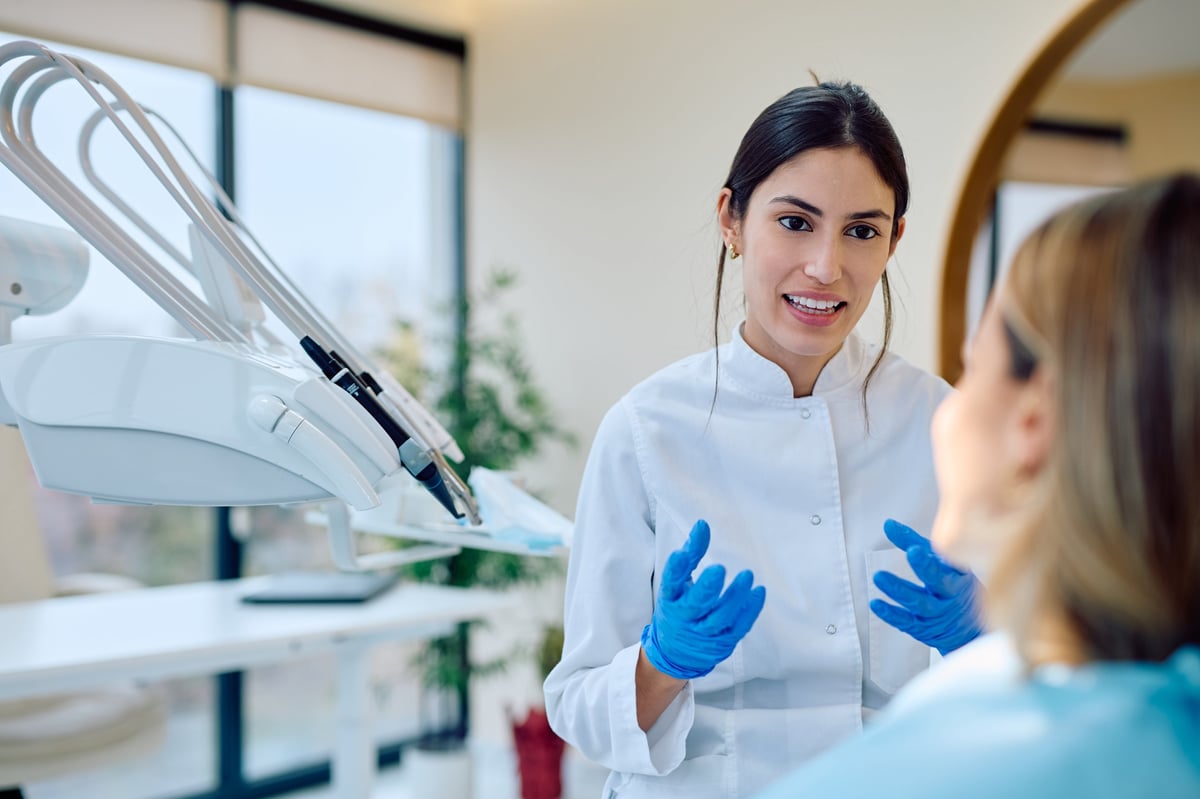 Young woman dentist consulting patient about oral health in modern dental office