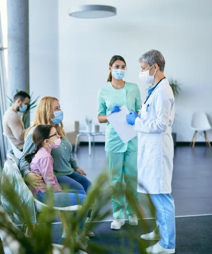Doctor and nurse in masks consulting with family patients in modern medical clinic waiting room