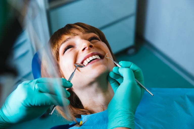 Young girl smiling with mouth open during dental exam, dentist wearing turquoise gloves holding tools