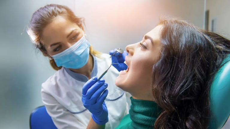 Dentist in mask and gloves performing oral examination on patient in dental chair